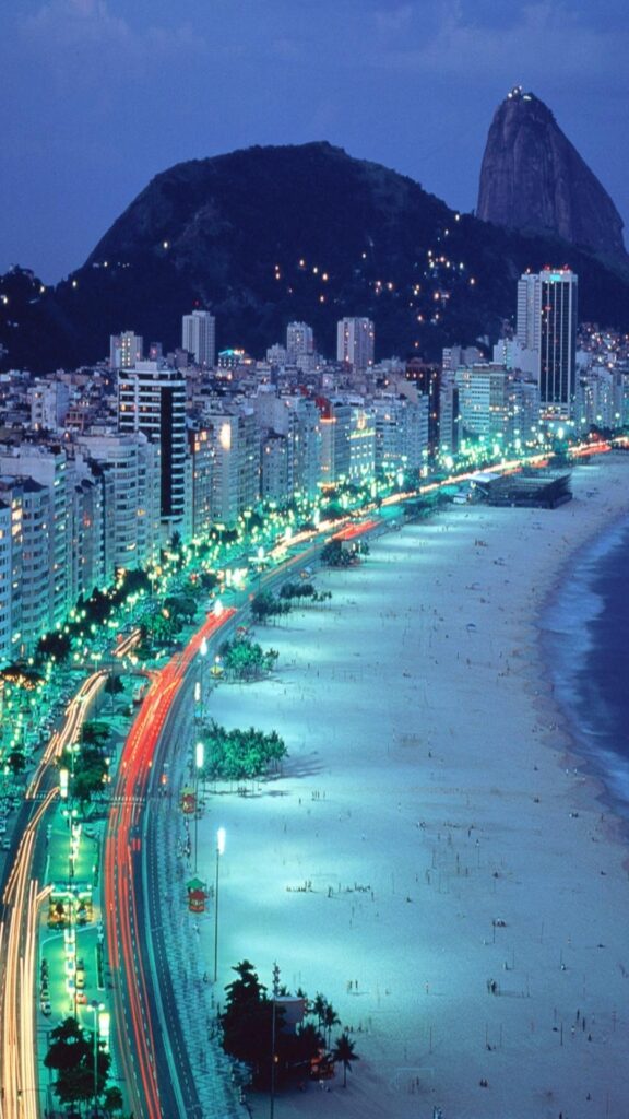 rio de janeiro iluminado por luzes e uma linda vista da praia nesse wallpaper para celular