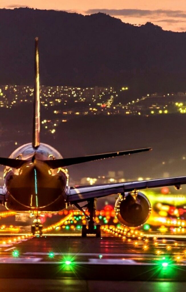 wallpaper para celular de um avião de passageiros decolando com as luzes da cidade ao fundo