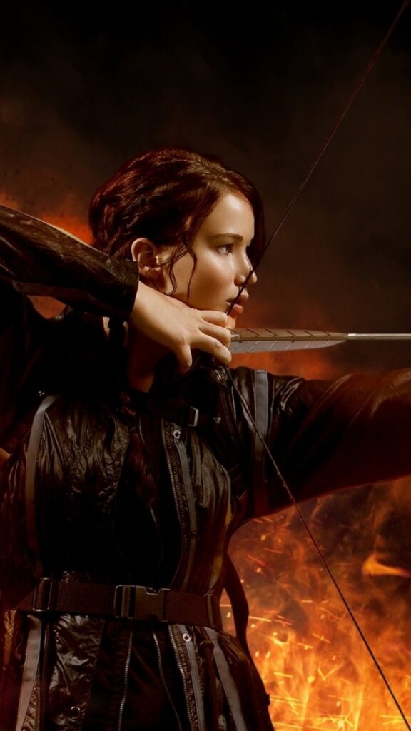 Katniss empunhando seu arco com determinação nesse papel de parede para celular, simbolizando a resiliência diante dos desafios mortais dos Jogos Vorazes.