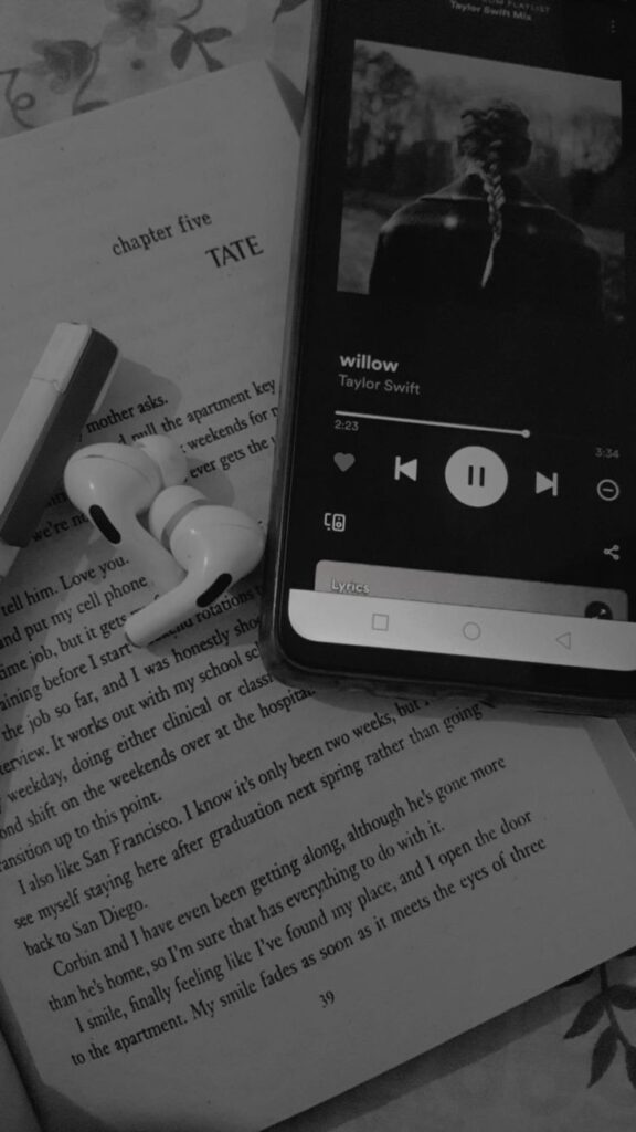 wallpaper para celular em preto e branco de um livros e um celular tocando Taylor Swift