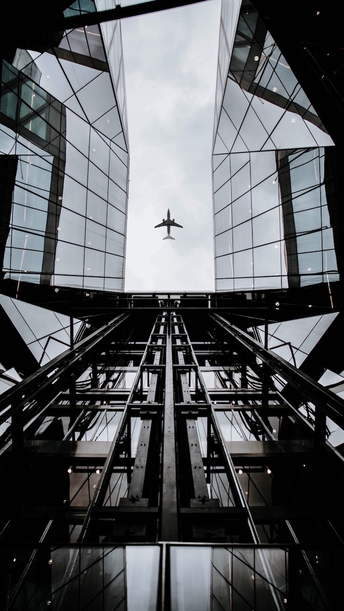 vista de baixo de um alto prédio com avião de fundo para papel de parede para celular